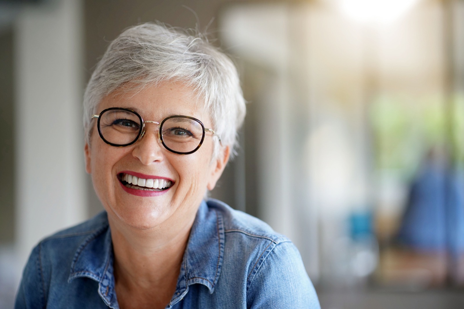 Smiling woman in her 50s wearing glasses, feeling good about her glaucoma treatment